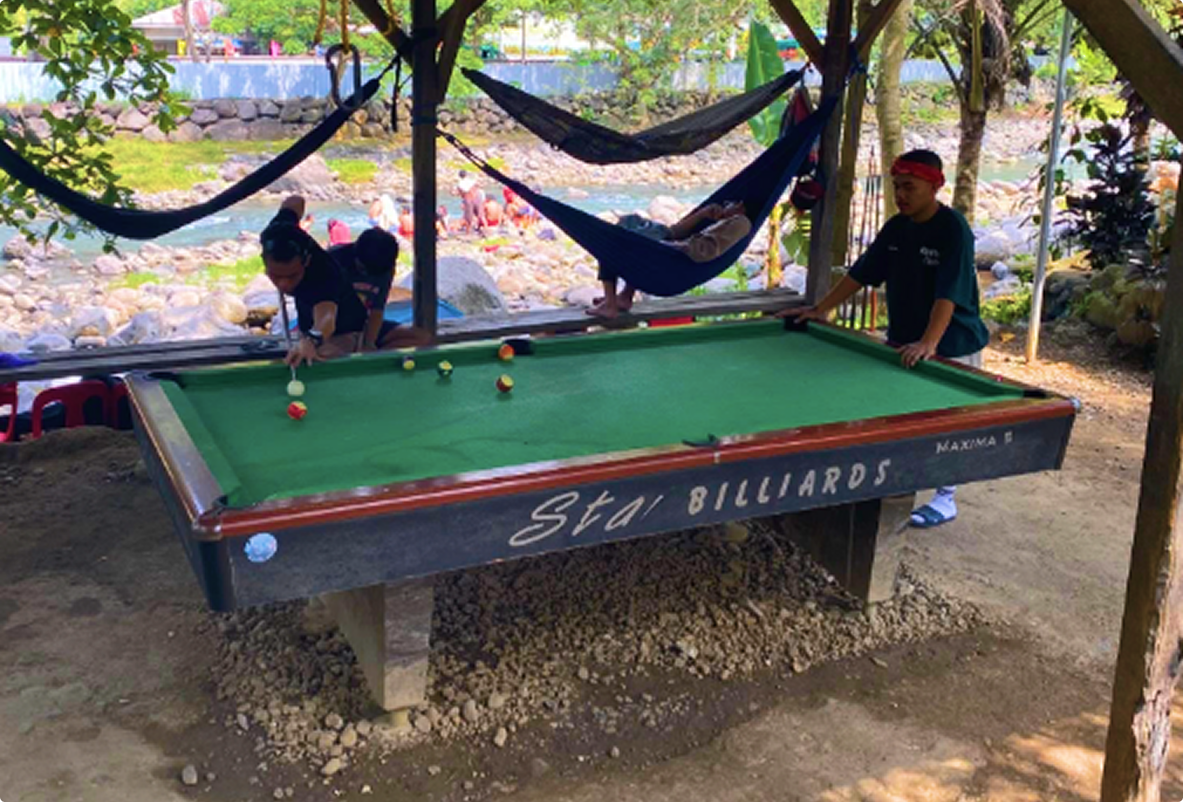 Guests playing billiards under a shaded area